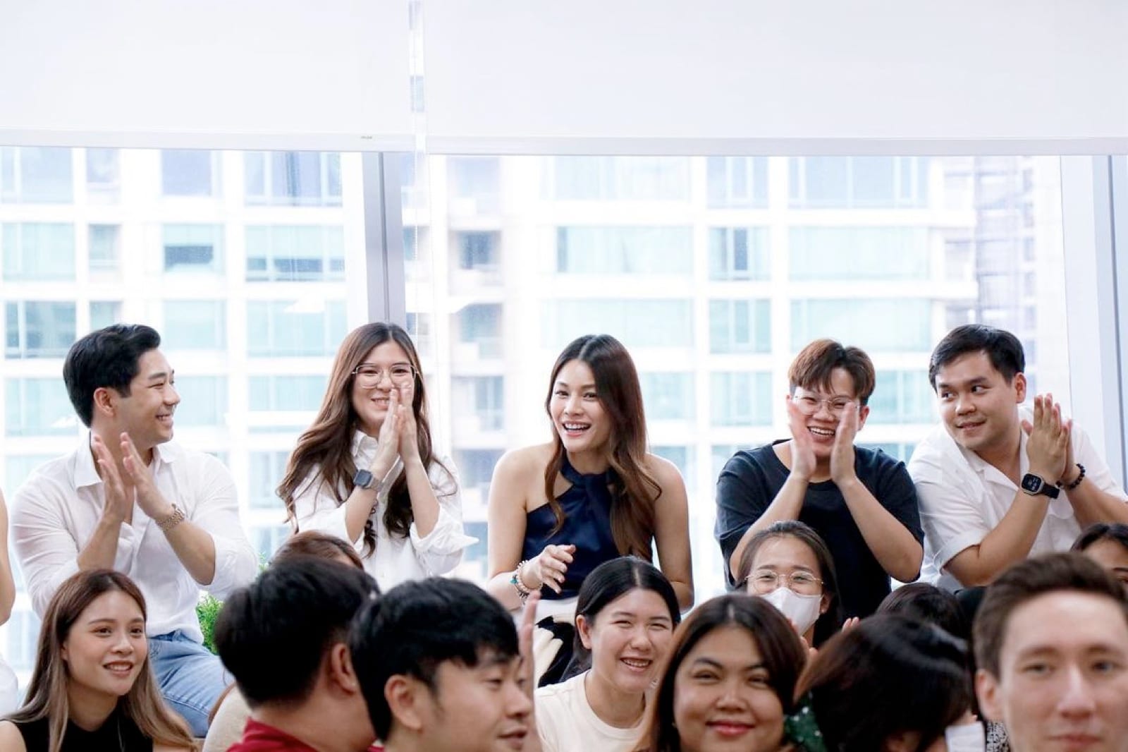 Primal staff applauding a colleague in a meeting room beside glass windows