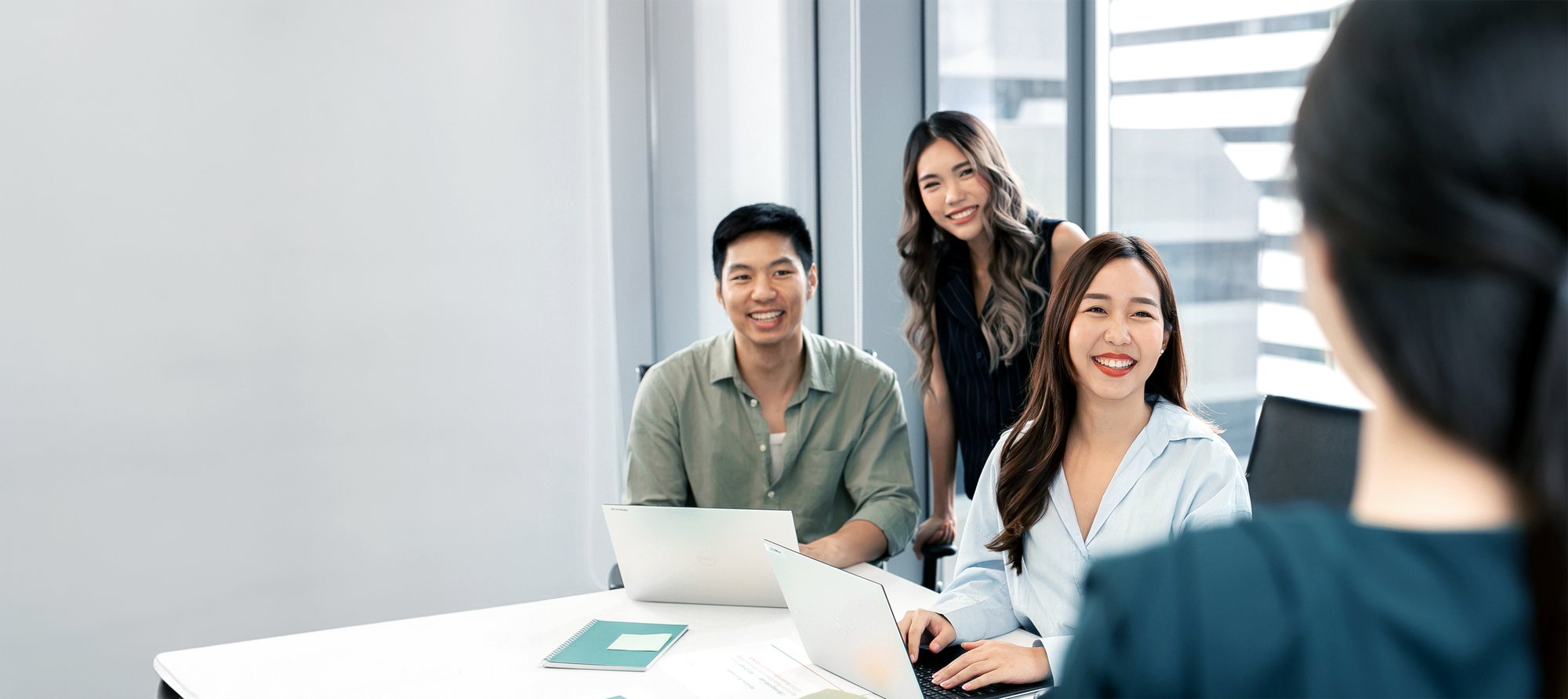 Primal team members smiling and collaborating around laptops in a meeting room