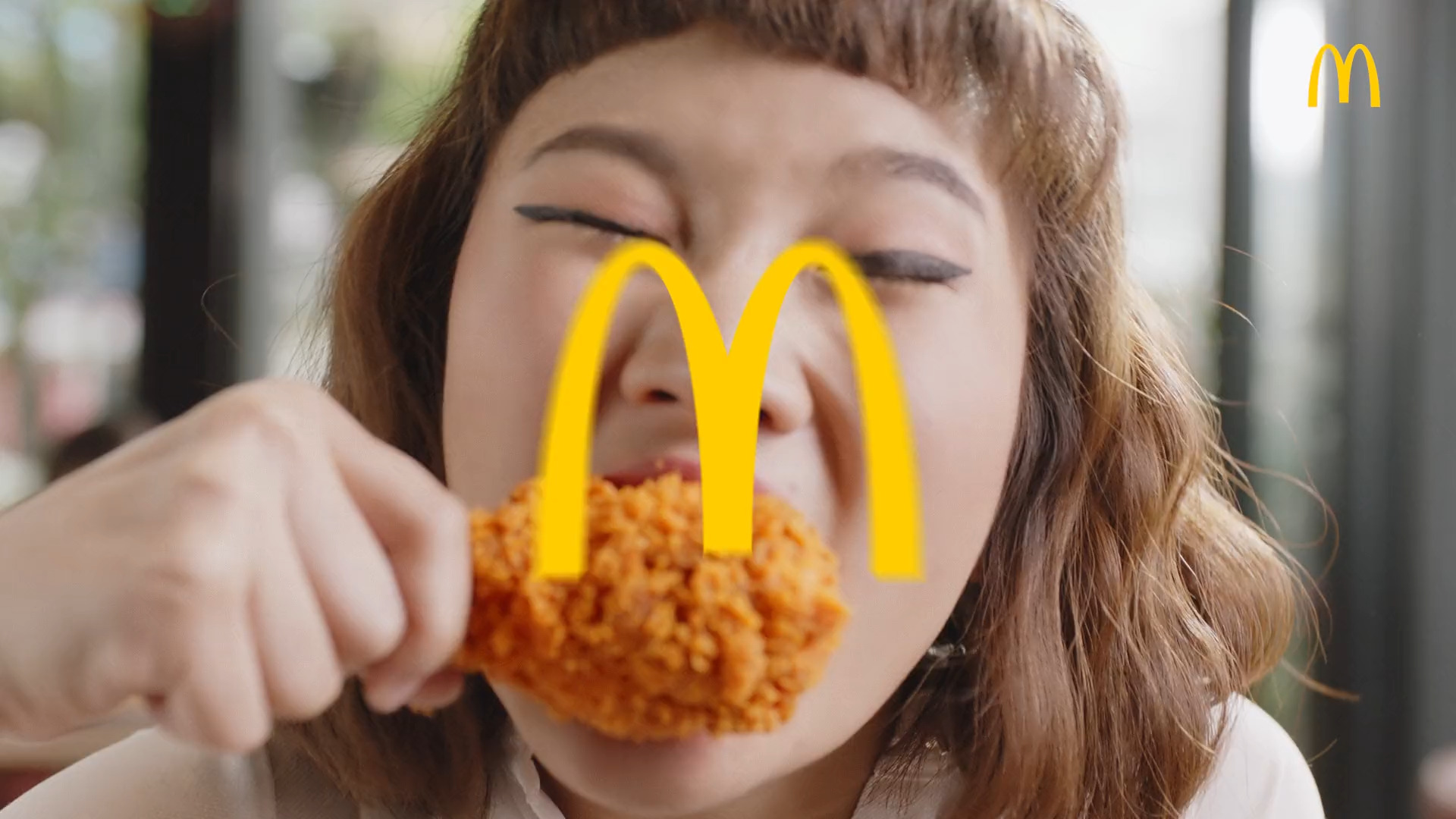 A woman eating McDonald's chicken, the golden arches framing the shot